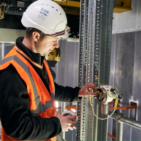 Is it time to upgrade your control panels? Image depicts a Woodward Group engineer wearing safety gear working on a control panel at a client site.