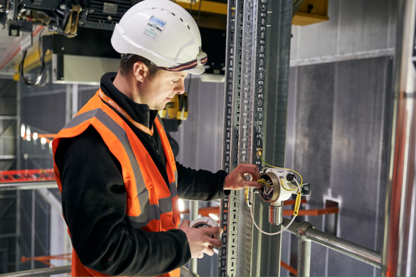 Is it time to upgrade your control panels? Image depicts a Woodward Group engineer wearing safety gear working on a control panel at a client site.